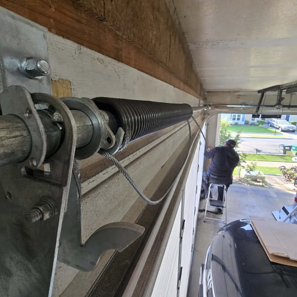 Technician performing garage door torsion spring repair services